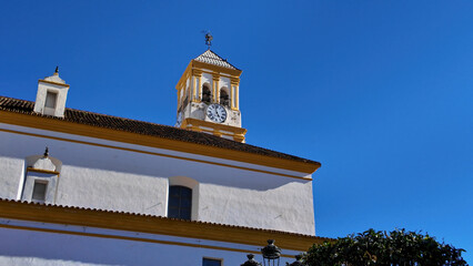 White and yellow church tower with clock in Marbella, Spain