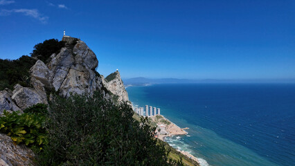 Gibraltar rock overlooking buildings and Mediterranean sea under blue sky