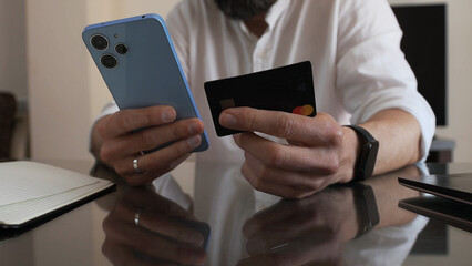 Close-Up of a Man Using Smartphone and Credit Card for Online Payment