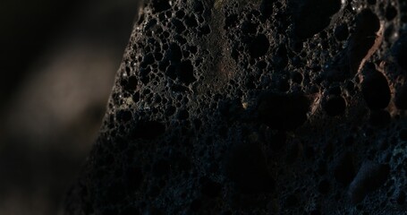 Macro shot of a dark volcanic rock with dramatic light and shadow