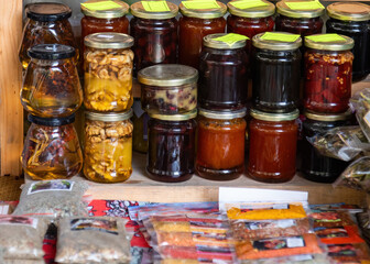 Jars of homemade preserves and herbs for sale at a market.