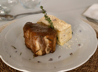 Wedding celebration table and main course arrangement. Gourmet food. Closeup view of a pork loin with a soft cream sauce and potato mille feuille