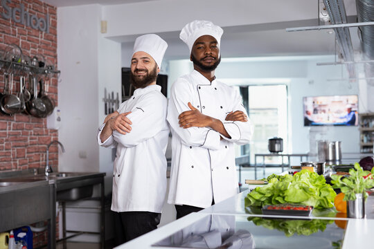 Diverse chefs in uniform preparing a delicious meal in a professional kitchen, preparing fresh ingredients to cook a gourmet dish on a stove. Using culinary tools to create a professional recipe.