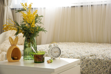 Bouquet of mimosa with cup of tea and Easter chocolate eggs