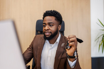 Portrait of interracial car seller sitting at office with car keys in hands and finishing contract...
