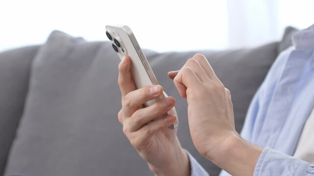 リビングでスマートフォンを使う男性の手元