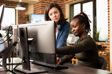 Production female team in creative agency brainstorms innovative ideas, using computer software to...