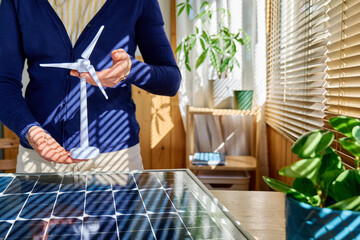 Anonymous business woman working in home office in renewable energy industry, showing eolic turbine model