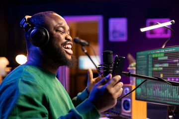 Songwriter producer recording a new track in home studio, singing on microphone to create an...