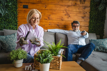 wife do gardening with potted plants while husband watch television