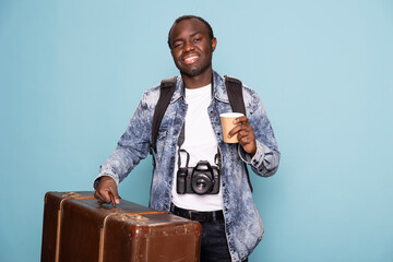 African american photographer dressed in a denim jacket carrying his luggage and backpack preparing...