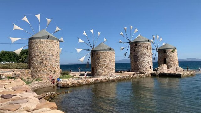 windmills on the seashore, tourists sunbathing on the beach