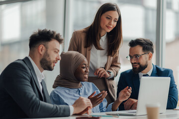 Business team collaborating on project using laptop in office