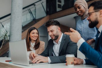 Business team collaborating on laptop in modern office