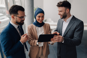 Business team using digital tablet, discussing work in modern office