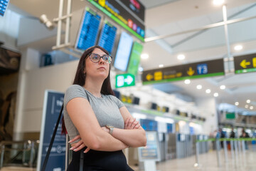 Young woman waiting for flight in airport terminal with crossed arms