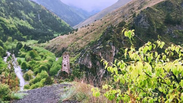 The tower complex is located inside the green mountains. The Republic of Ingushetia, Russia. View of the defensive towers of Ingushetia in the North Caucasus on a cloudy day in spring. 4K