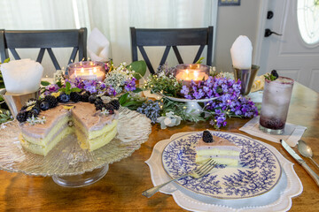 Lilac decorated table with a Chantilly Cake with blackberries and blueberries over a light blackberry frosting
