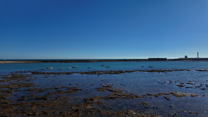 Fishing boats floating on the sea in Cadiz, Spain, during a sunny day with blue sky