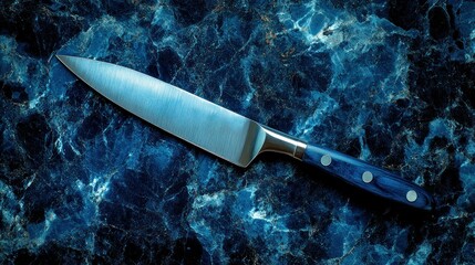 Shiny knife on marbled blue surface with silver handle and blade detail