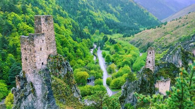The tower complex is located inside the green mountains. The Republic of Ingushetia, Russia. View of the defensive towers of Ingushetia in the North Caucasus on a cloudy day in spring. 4K