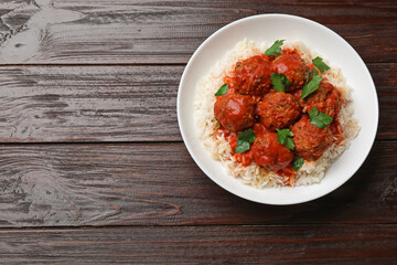Tasty meatballs with sauce and rice on wooden table, top view. Space for text