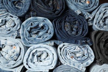 Different stylish rolled jeans as background, top view
