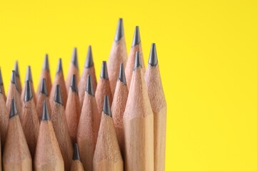 Many graphite pencils on yellow background, closeup