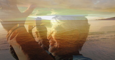 Composite of happy senior couple walking carrying surfboards on heads, and beach at sunset