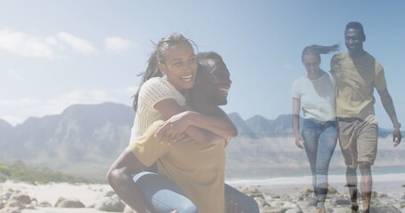 Composite of happy african american couple piggybacking, and embracing walking on beach