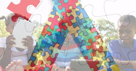 Image of colourful puzzle pieces ribbon over school children using tablets