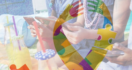 Image of colourful puzzle pieces ribbon over friends using smartphone and tablet