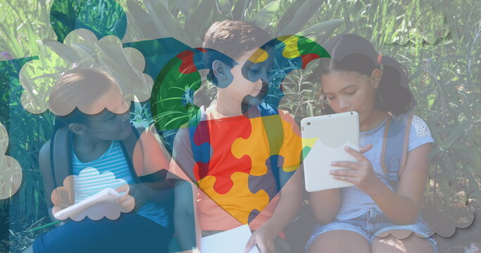 Image of colourful puzzle pieces heart over school children using tablets