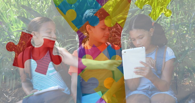 Image of colourful puzzle pieces hand over school children using tablets