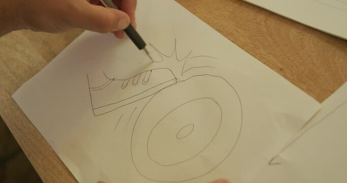 Person drawing silly picture of shoe squeaking against moving wheel, closeup shot