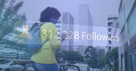 Image of social media notification over african american woman in mask using phone in street