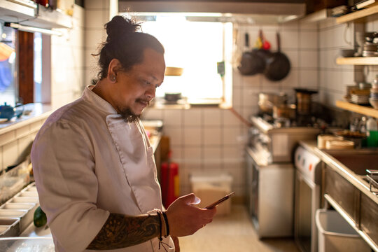 Sushi chef using smartphone in restaurant kitchen