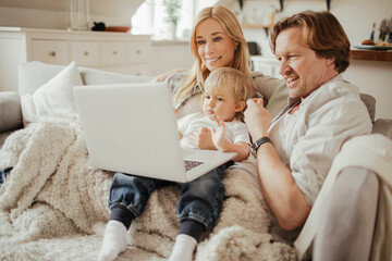 Obraz premium Young family watching a movie on their laptop at home