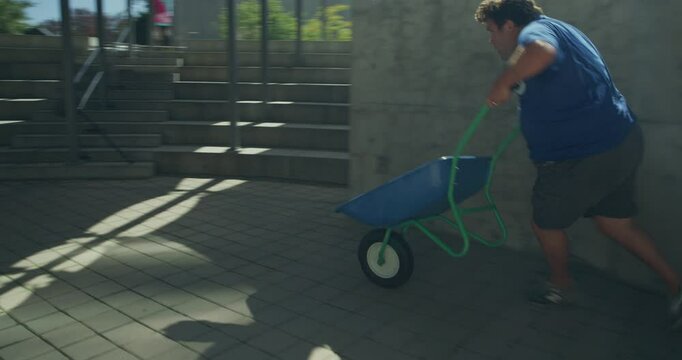 Guy doing silly wheel barrow trick on cement wall - steady cam shot