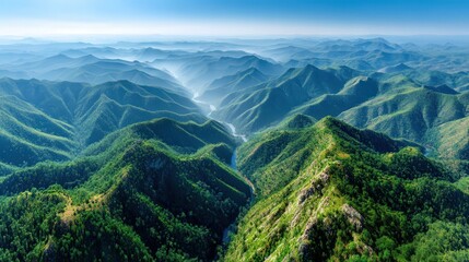 Serene aerial shot of lush green mountain range surrounded by majestic peaks and rolling hills under clear blue sky