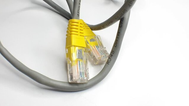 Close-up of two RJ45 Ethernet connectors with yellow ends, connected to a grey cable, on a white background.