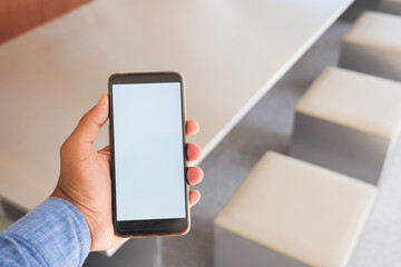 Person holding smartphone in modern workspace during daytime