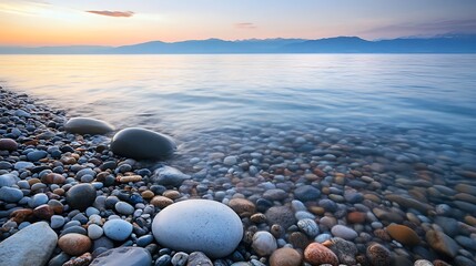 Obraz premium Serene lake shore at dawn with smooth pebbles.