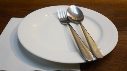 A clean white plate and silverware are placed on the table, beautifully lit by soft lighting