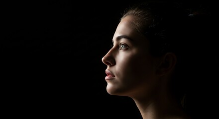 Fototapeta premium Profile Portrait of a Woman with Dramatic Lighting on Black Background