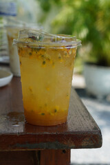Passion Fruit Soda in a clear plastic glass. decorated with flowers and leaves on wooden table, blur nature background, fruit, nature, drink, fresh, copy space