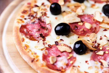 Pizza with salami and mozzarella cheese. Wooden background. Soft focus. Close up.	