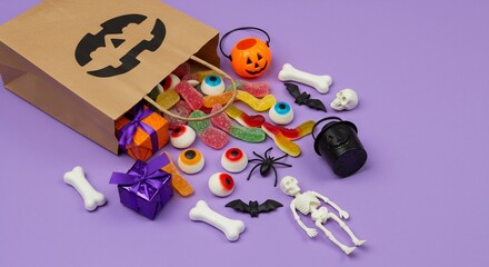 Obraz premium Spooky Halloween Treats Spilling from a Jack-o'-Lantern Decorated Paper Bag onto a Purple Background