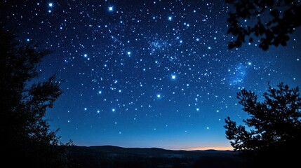 Starry night sky with a silhouette of trees and distant hills.