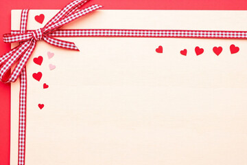 red hearts on a wooden background with a red and white checkered ribbon